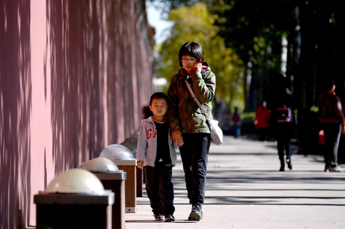 A woman and a child walk along a road in Beijing on October 31. China announced the end of its hugely controversial one-child policy on October 29.