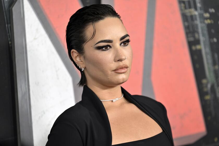 Demi Lovato poses in an all black outfit and a silver choker.