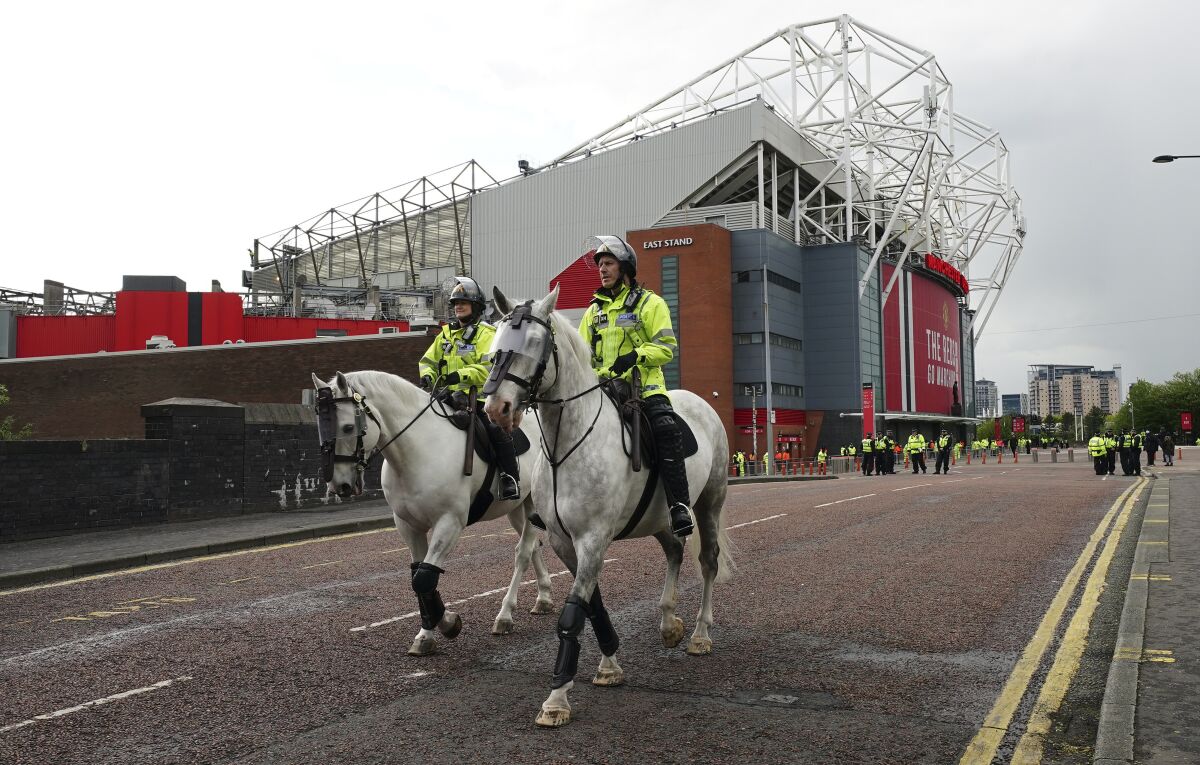 Police officers on horseback patrol outside the Old Trafford stadium in Manchester, England, Tuesday, May 11, 2021 ahead of the English Premier League soccer match between Manchester United and Leicester City. This is the first Manchester United home match since fans protested against American owner Joel Glazer, forcing the postponement of the team's Premier League game against Liverpool. The protests prompted Glazer to publish a letter in which he pledged to accelerate discussions with fans about supporters being able to have a greater say at the club. (AP Photo/Jon Super)