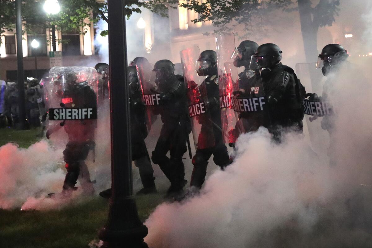 Mientras el gas lacrimógeno llena el aire, la policía intenta hacer retroceder a los manifestantes.