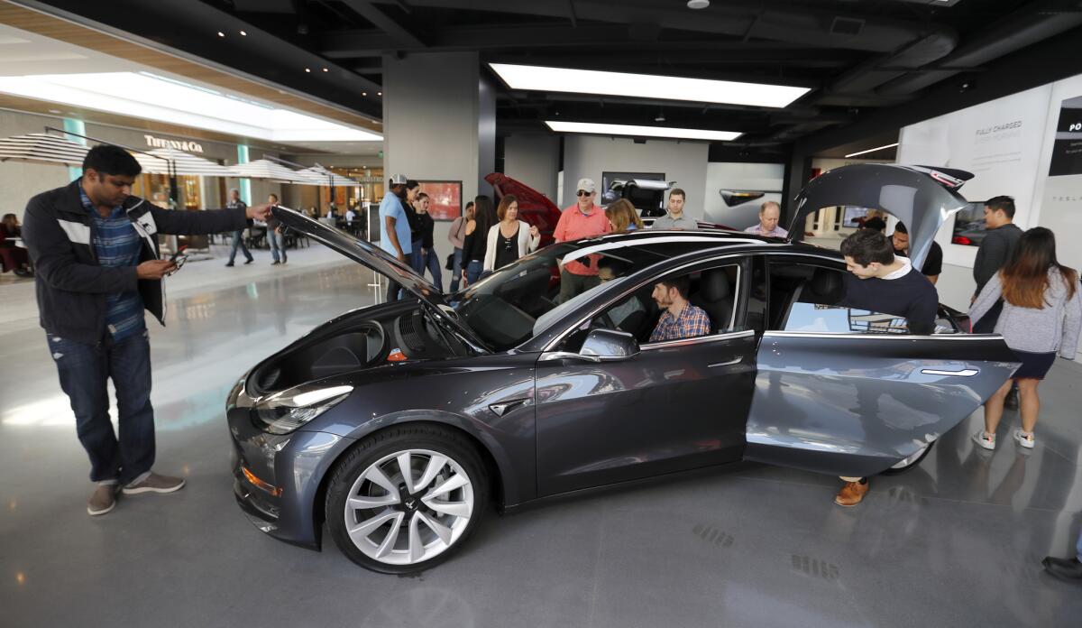 People browse the Model 3 at the Tesla showroom at the Westfield in Century City.