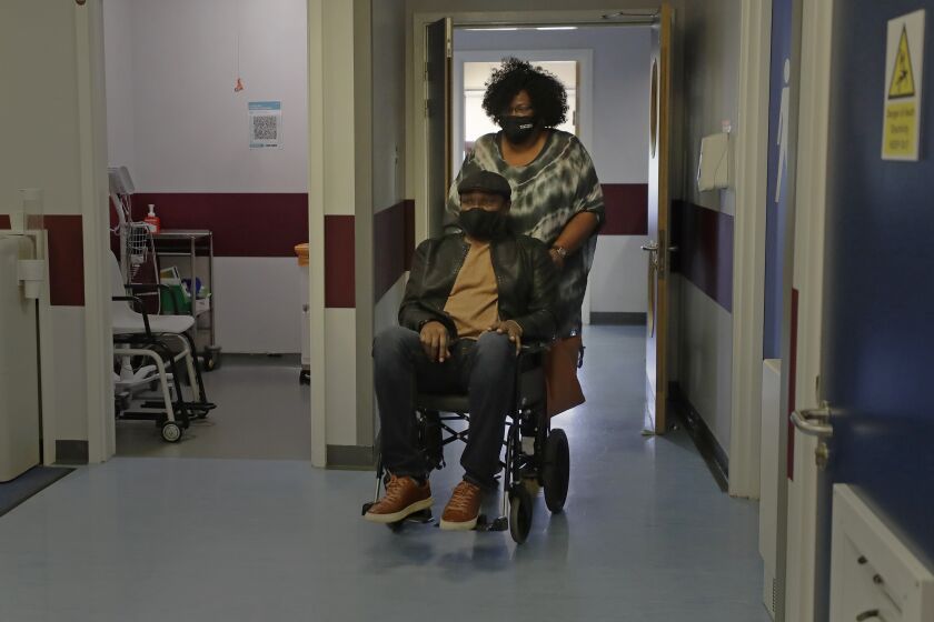 Long COVID patient Barry Bwalya is pushed by his wife Barbara at King George Hospital in London.