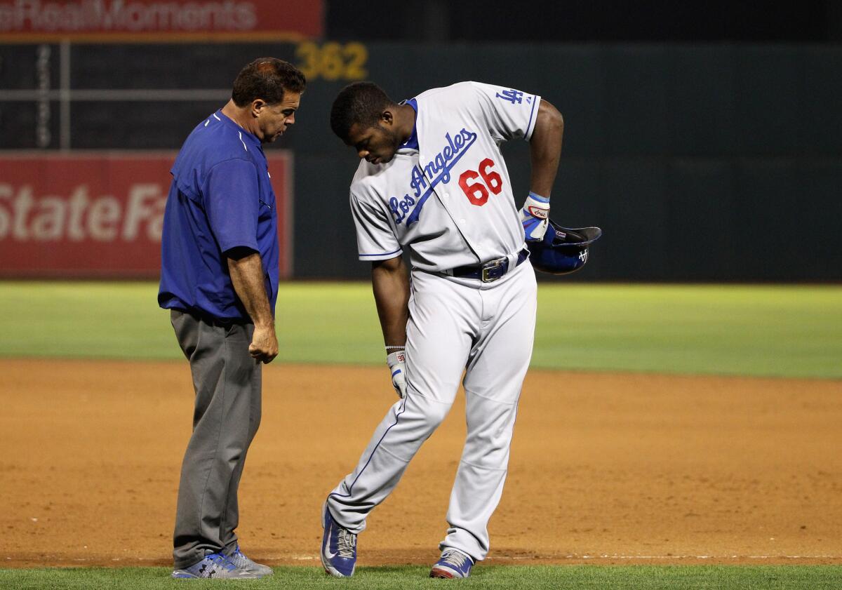 Dodgers outfielder Yasiel Puig has his leg checked out by Stan Conte, the team's vice president of medical services, on Aug. 18.
