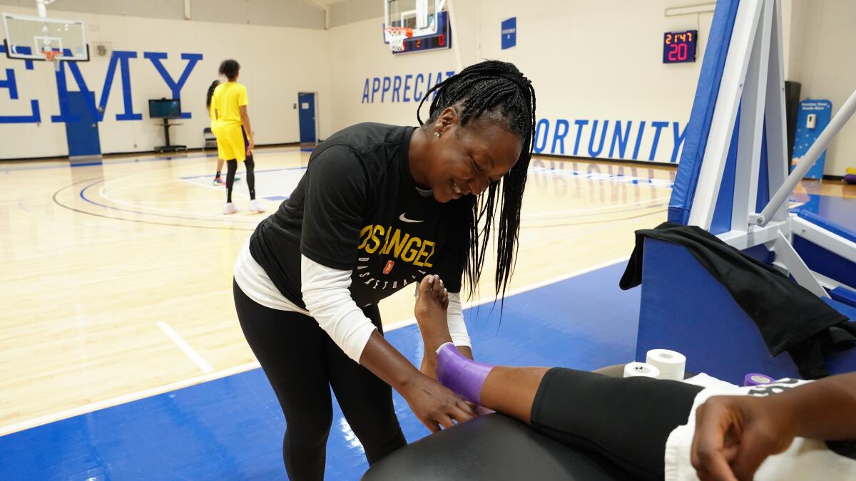 Head athletic trainer Courtney Watson tapes the ankle of a Sparks player.