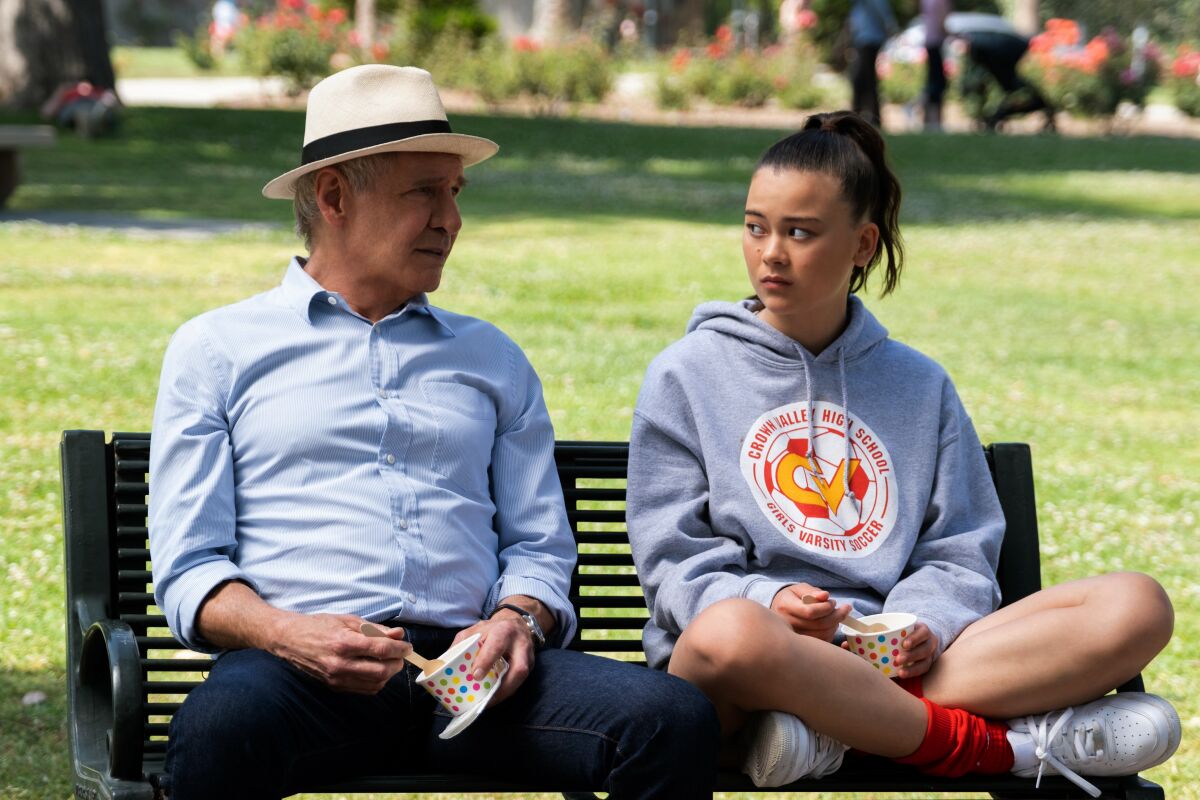 A grandfatherly man (Harrison Ford) sits with a teen girl (Lukita Maxwell), the only person he's nice to, in "Shrinking."