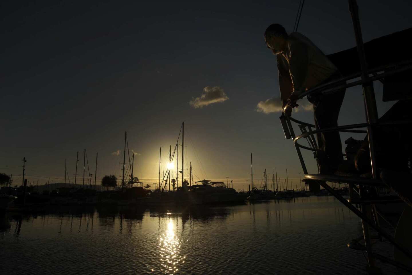 Live-aboard boat owner John Loftus watches the setting sun from the deck of his 43-foot sailboat moored at the Colonial Yacht Anchorage in Wilmington. He is among 95 boat owners who were served with eviction notices last month.