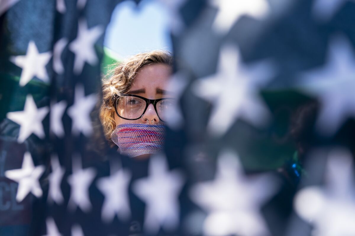 Emma Rousseau of Oakland, N.J., her mouth bound with a red, white and blue netting, attends a rally on the Fourth of July to protest for abortion rights, at Lafayette Park in front of the White House in Washington, Monday, July 4, 2022. (AP Photo/Andrew Harnik)