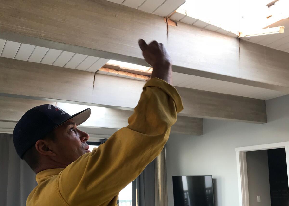 Santa Barbara County Fire Capt. Bryan Fernandez points to a hole that firefighters cut in the roof of a condo to keep flames from spreading.