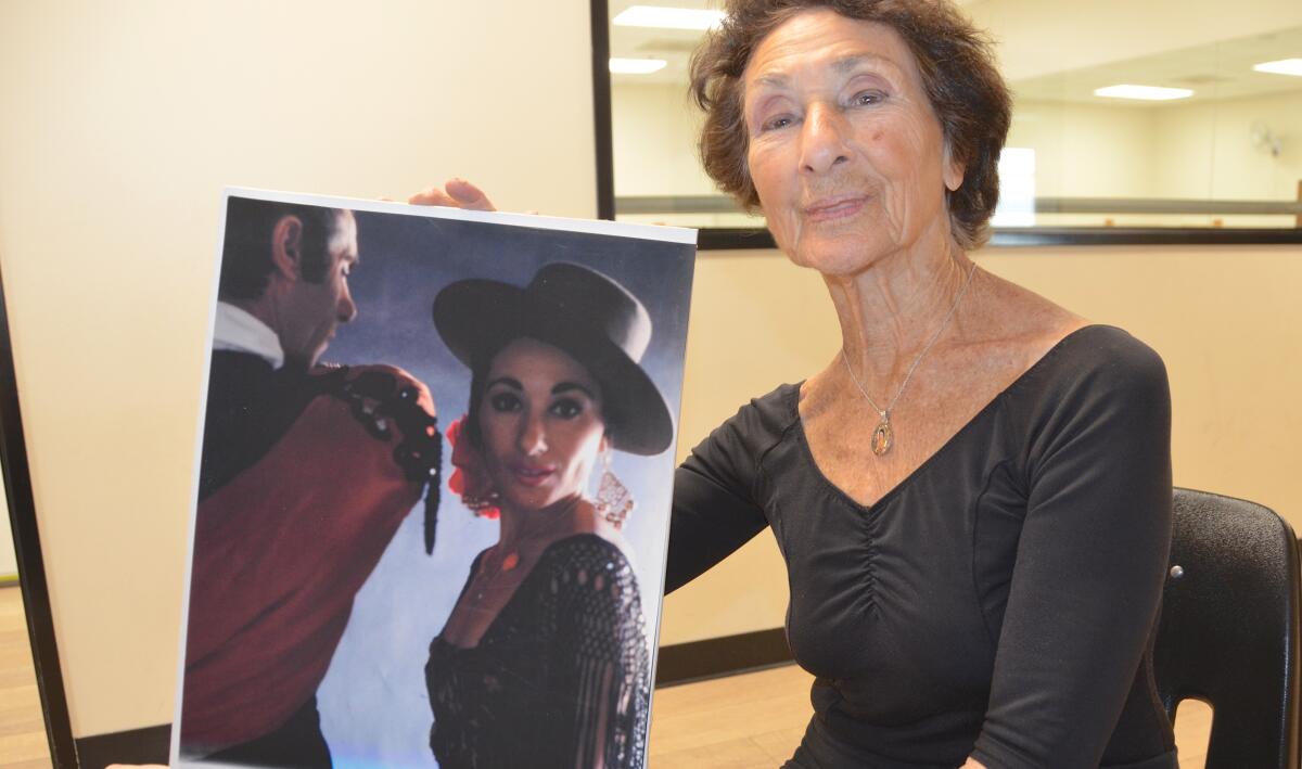 Miss Pepa Dodge holds a photo of herself performing dance during the early days of her career.