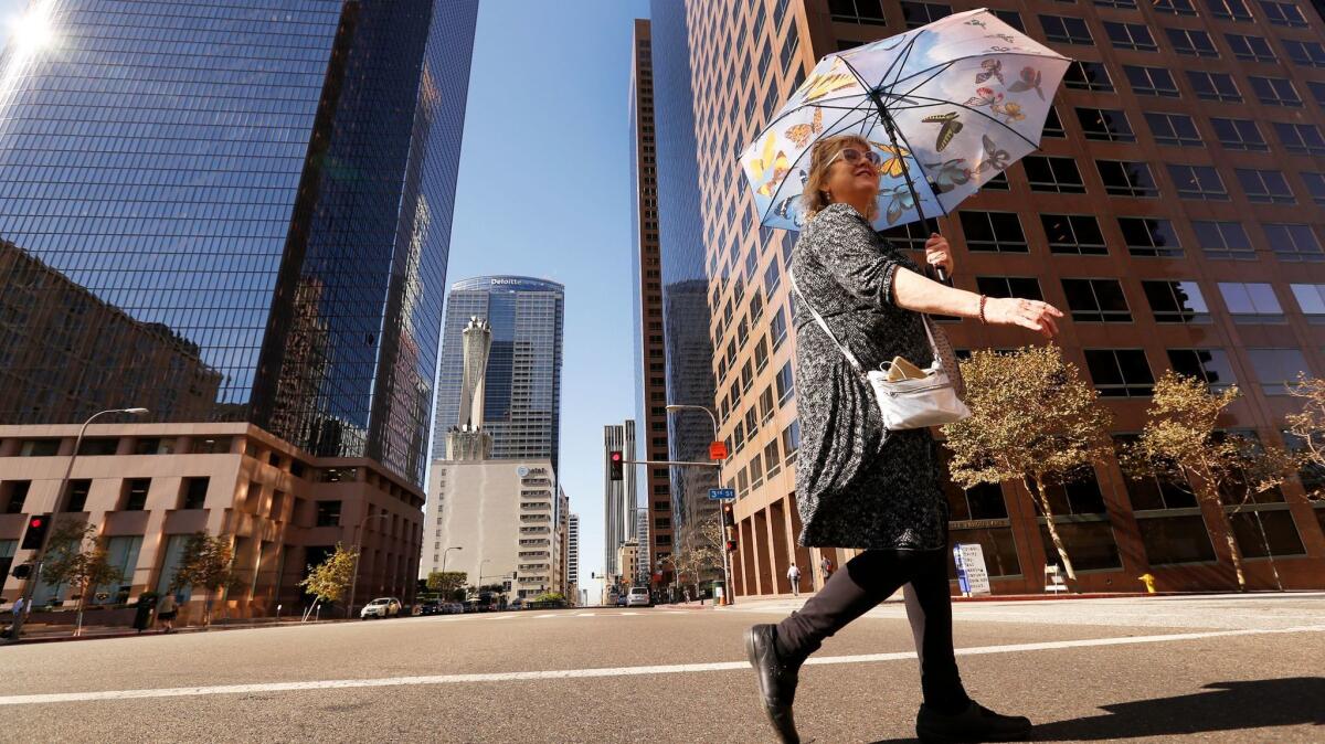 Terrie Lee Duba uses an umbrella to shade herself from the sun as she walks to a bus stop in downtown Los Angeles.