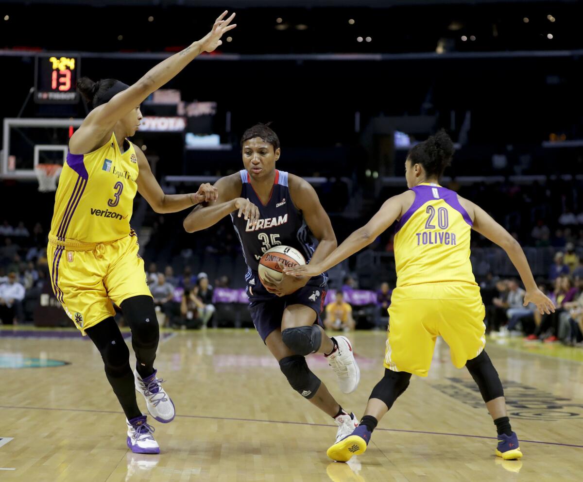 Dream guard Angel McCoughtry drives between Sparks forward Candace Parker (3) and guard Kristi Toliver (20) during the first half.