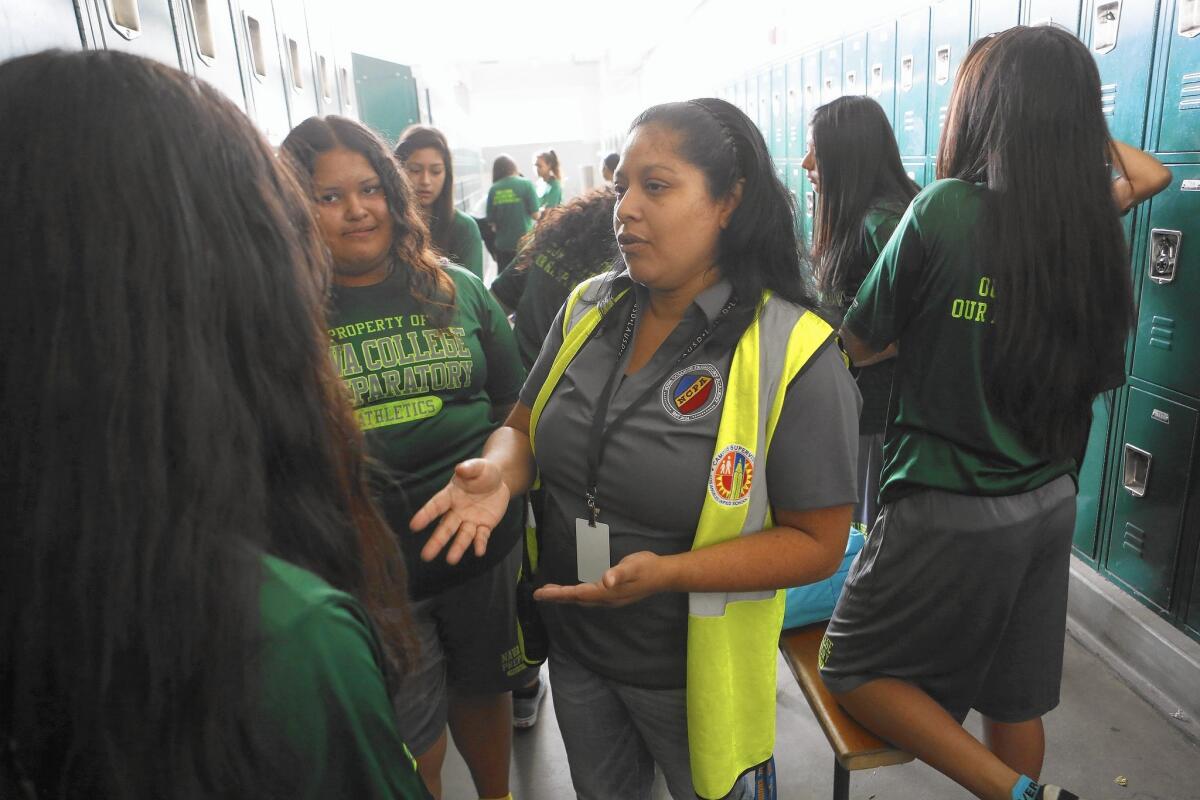 Supervisor aide Maria Melendrez talks with students in the girls locker room at Nava College Preparatory Academy. Melendrez was one of the parents who spearheaded the school's founding.