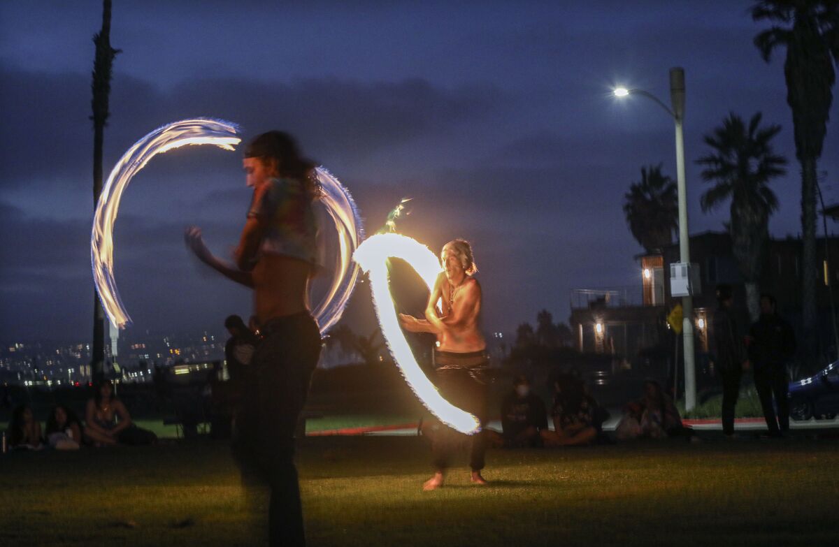People twirl fire batons in Ocean Beach.