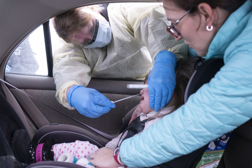 A medical professional collects a sample from a young girl at a drive-through coronavirus screening clinic at Sainte Justine Children Hospital in Montreal, Thursday, March 19, 2020. (Paul Chiasson/The Canadian Press via AP)
