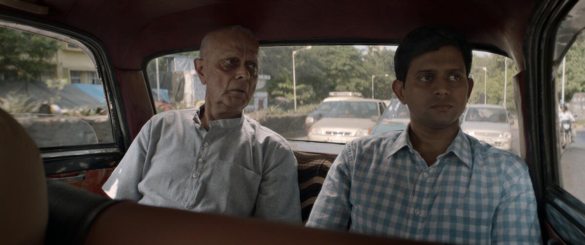 Two men sit in the rear seat of a vehicle.