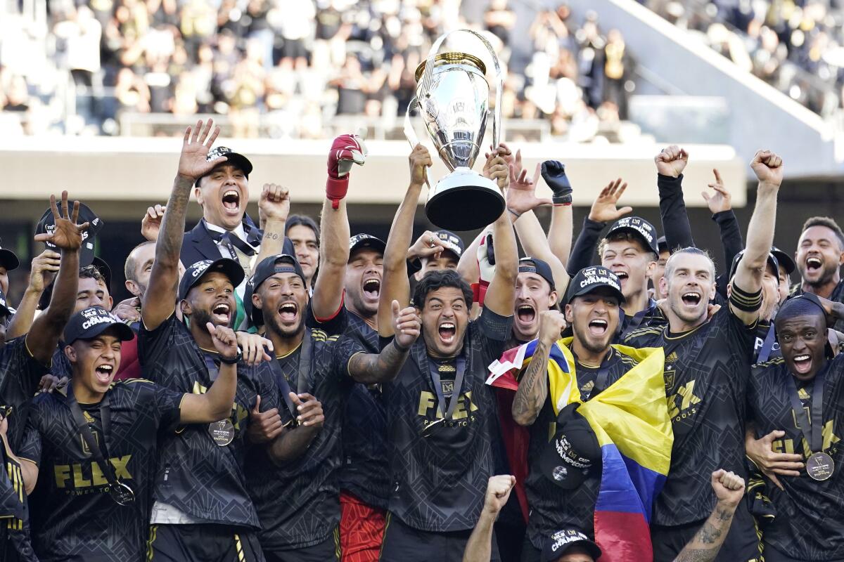 Carlos Vela hoists a trophy as he and teammates celebrate their championship