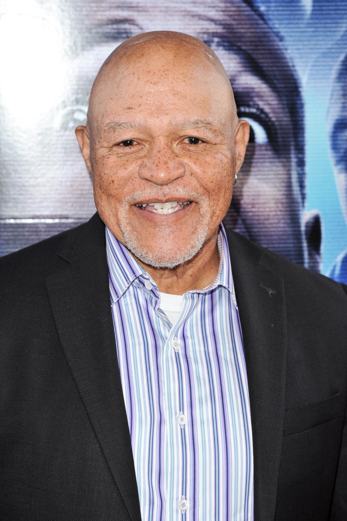 John Beasley, smiling, wears a striped shirt and a suit jacket