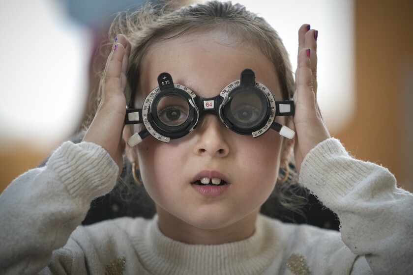 A little girl adjusts testing glasses during an eyesight examination performed by volunteer ophthalmologists working with the humanitarian organization Casa Buna, or Good House, in Nucsoara, Romania, Saturday, May 29, 2021. Dozens of disadvantaged young Romanian children got a chance to get their eyesight examined for the first time in their lives at an event on Saturday in a remote village in the country's southern Carpathian Mountains. (AP Photo/Vadim Ghirda)