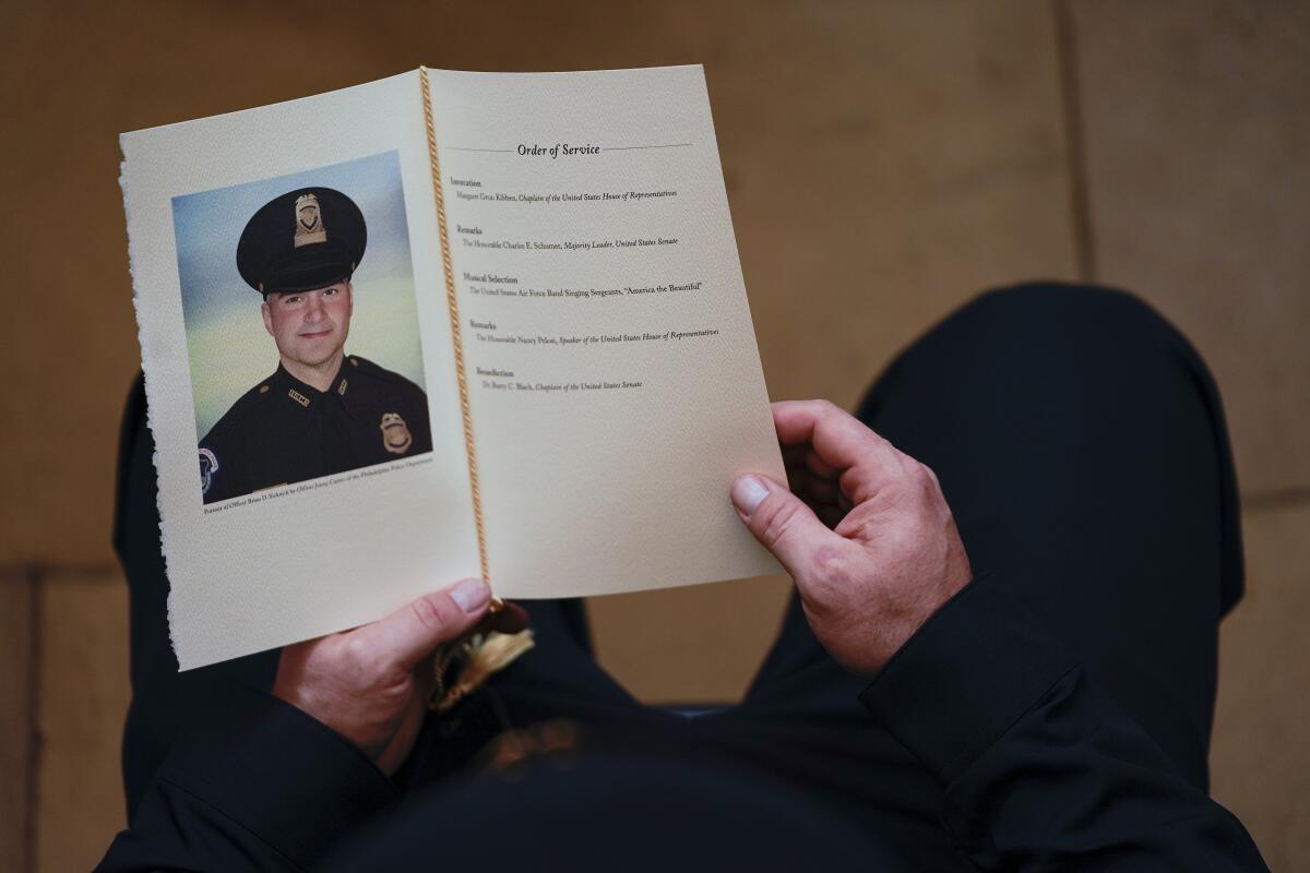 A police officer holds a funeral program for a fellow officer.