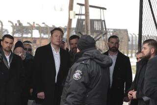 Tesla and SpaceX's CEO Elon Musk, centre, walks during his visit to the site of the Auschwitz-Birkenau Nazi German death camp in Oswiecim, Poland, on Monday, Jan. 22, 2024. The private visit was apparently in response to calls from some Jewish religious leaders for Musk to see with his own eyes the most symbolic site of the horrors of the Holocaust. (AP Photo/Andrzej Rudiak)