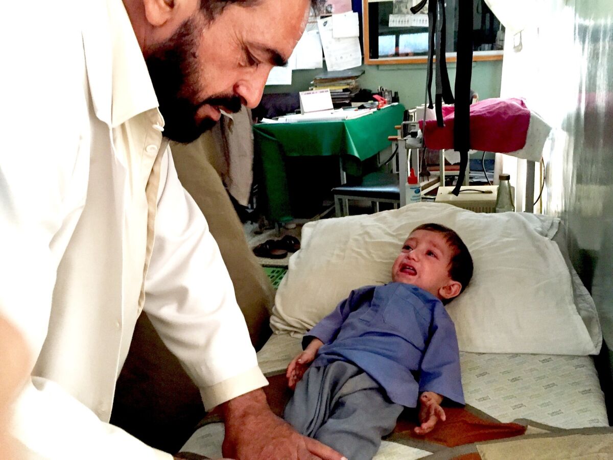 Khaksar, an 18-month-old polio patient, is examined by physiotherapist Mohammad Nabi at a hospital in Asadabad, Afghanistan.