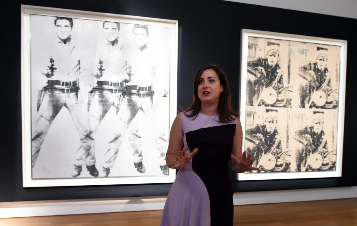 A Christie's employee speaks about Andy Warhol's "Triple Elvis" and "Four Marlons" during a media preview Oct. 31 in New York.