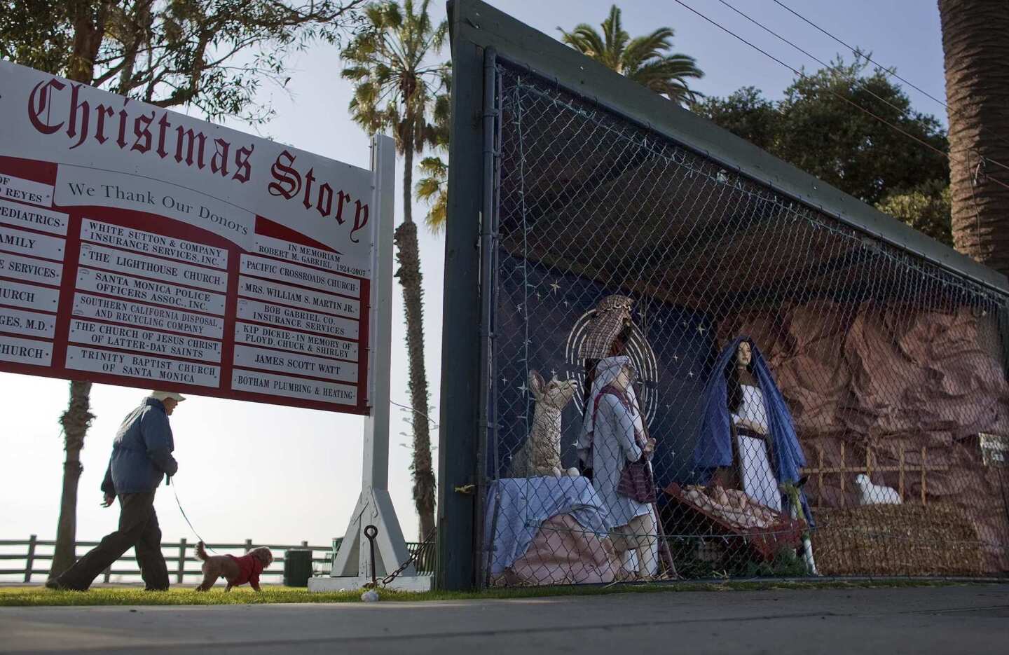 A woman walks her dog along the dirt path behind the Nativity scene at Pacific Palisades Park along Ocean Avenue.