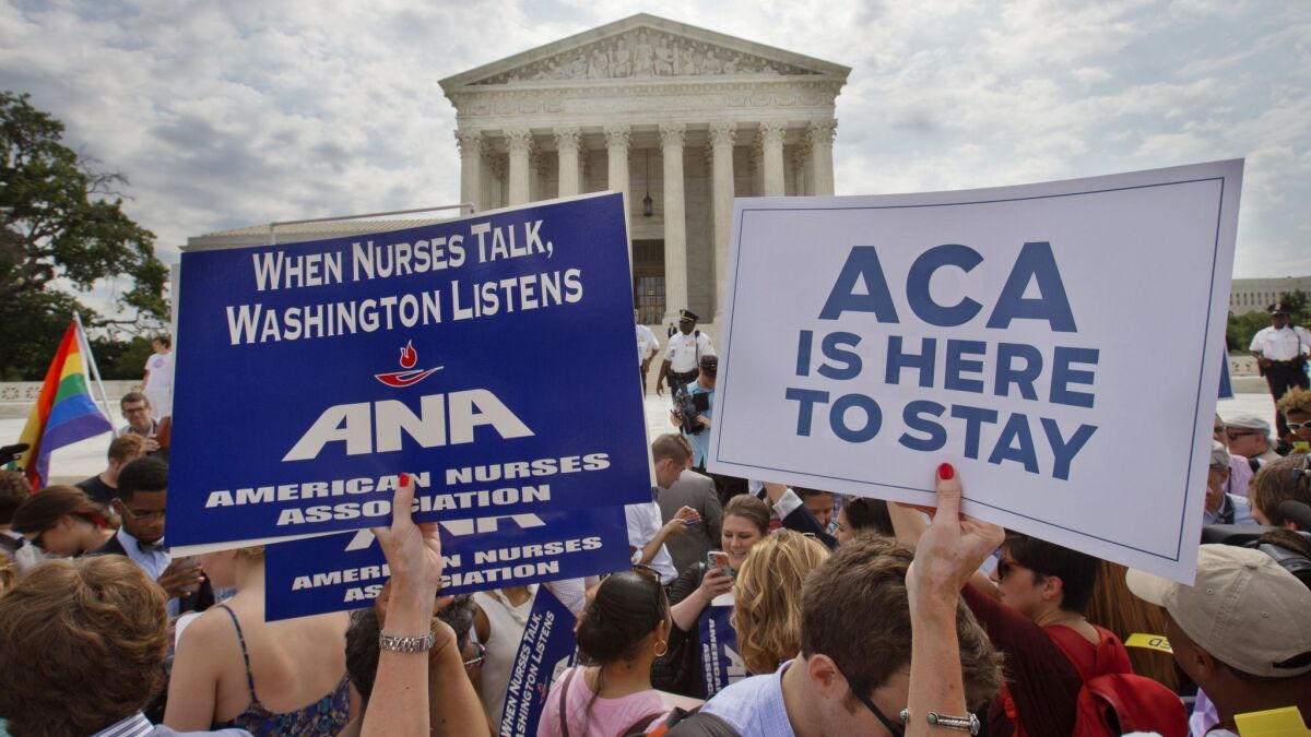 Supporters of the Affordable Care Act hold up signs outside the Supreme Court in June 2015.