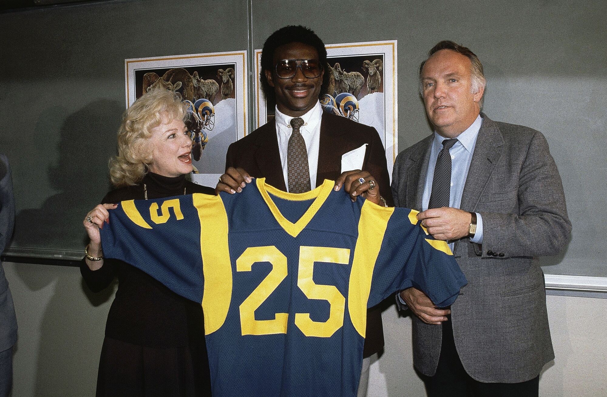 Eric Dickerson, hold up a Rams jersey with team owner Georgia Frontiere, left, and and coach John Robinson.