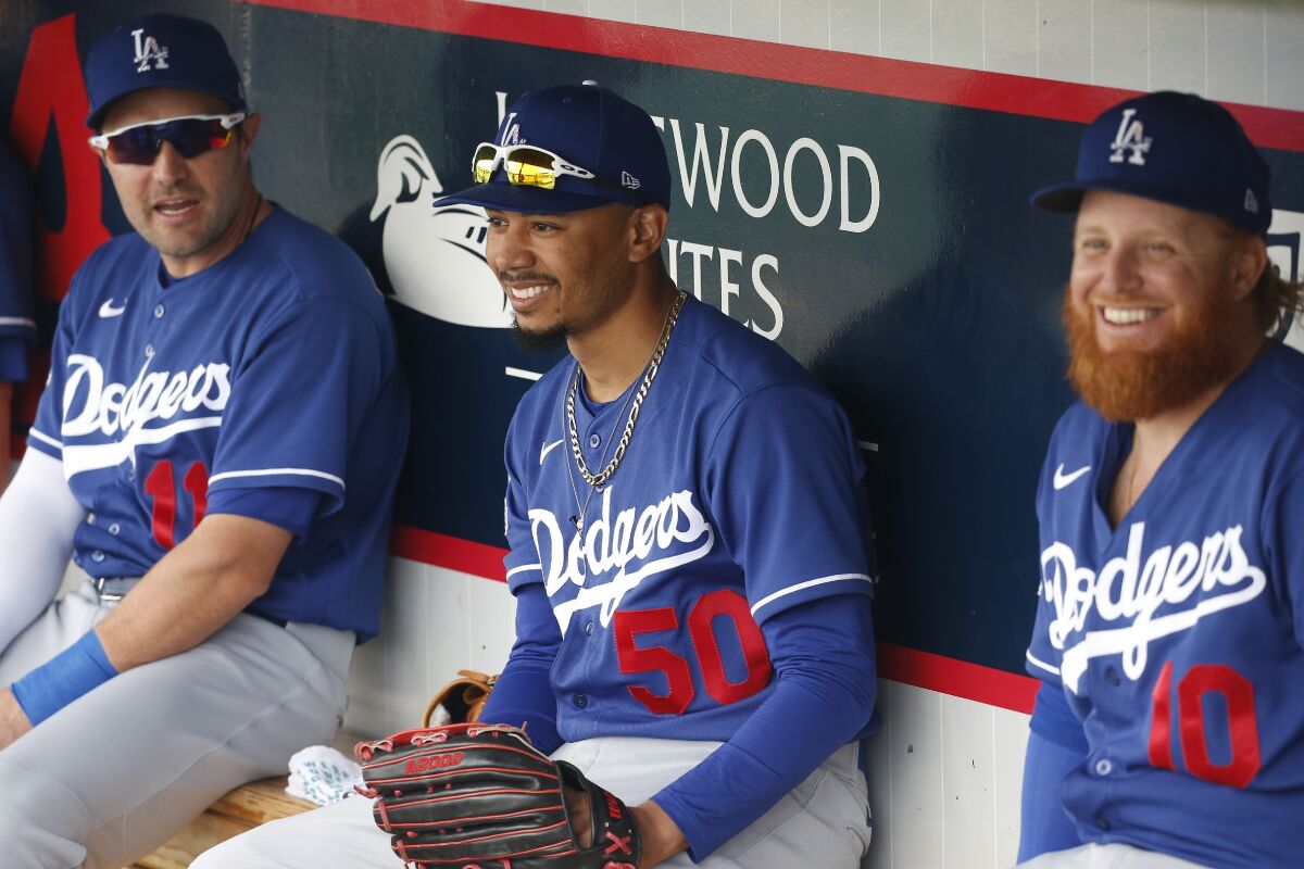 The Dodgers' A.J. Pollock, left, Mookie Betts and Justin Turner talk in the dugout before a spring training game this month.