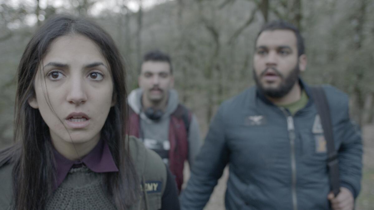 A woman and two men in a wooded area in the movie "Dachra."