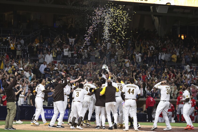 The San Diego Padres celebrate at home plate after Victor Caratini hit a home run against the Cincinnati Reds in the ninth inning of a baseball game Thursday, June 17, 2021, in San Diego. (AP Photo/Derrick Tuskan)