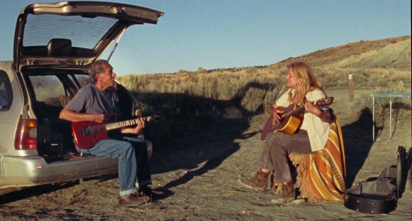 Two people play guitar in the outdoors