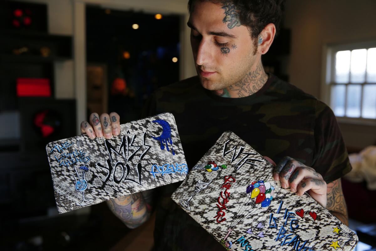 Graphic designer Josh Grunfeld holds two hand-painted clutches that he designed.