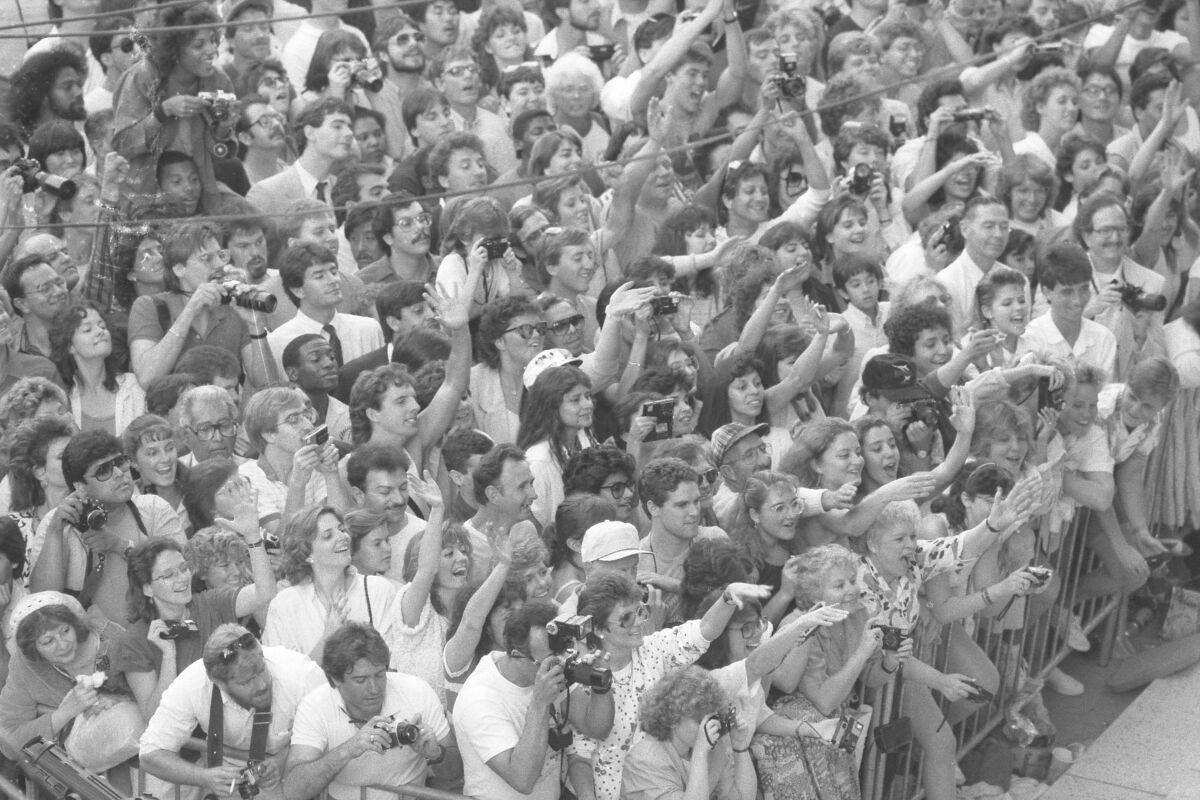 Spectators waving and taking photographs outside the 59th Academy Awards