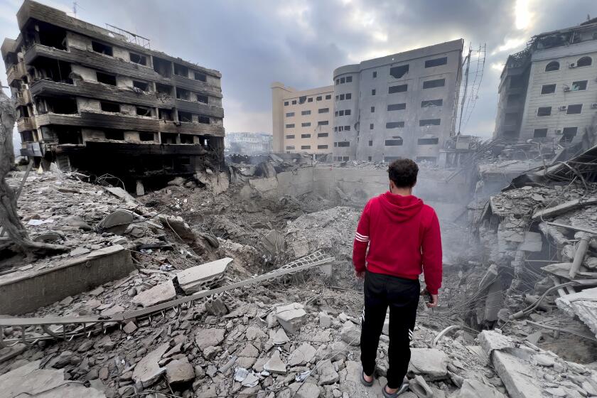 FILE - A man looks at destroyed buildings hit by Israeli airstrikes in Dahiyeh, Beirut, Lebanon, Monday, Oct. 7, 2024. Now in Lebanon, the Israeli military tells residents that they live near "facilities and interests" belonging to the militant Hezbollah group that they will strike soon. These warnings often come ahead of a series of overnight strikes on buildings in the Beirut southern suburbs, though there often are far more strikes than warned about. (AP Photo/Hussein Malla, File)