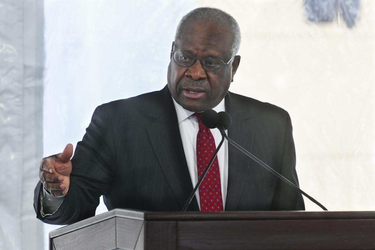 Clarence Thomas stands behind a podium.