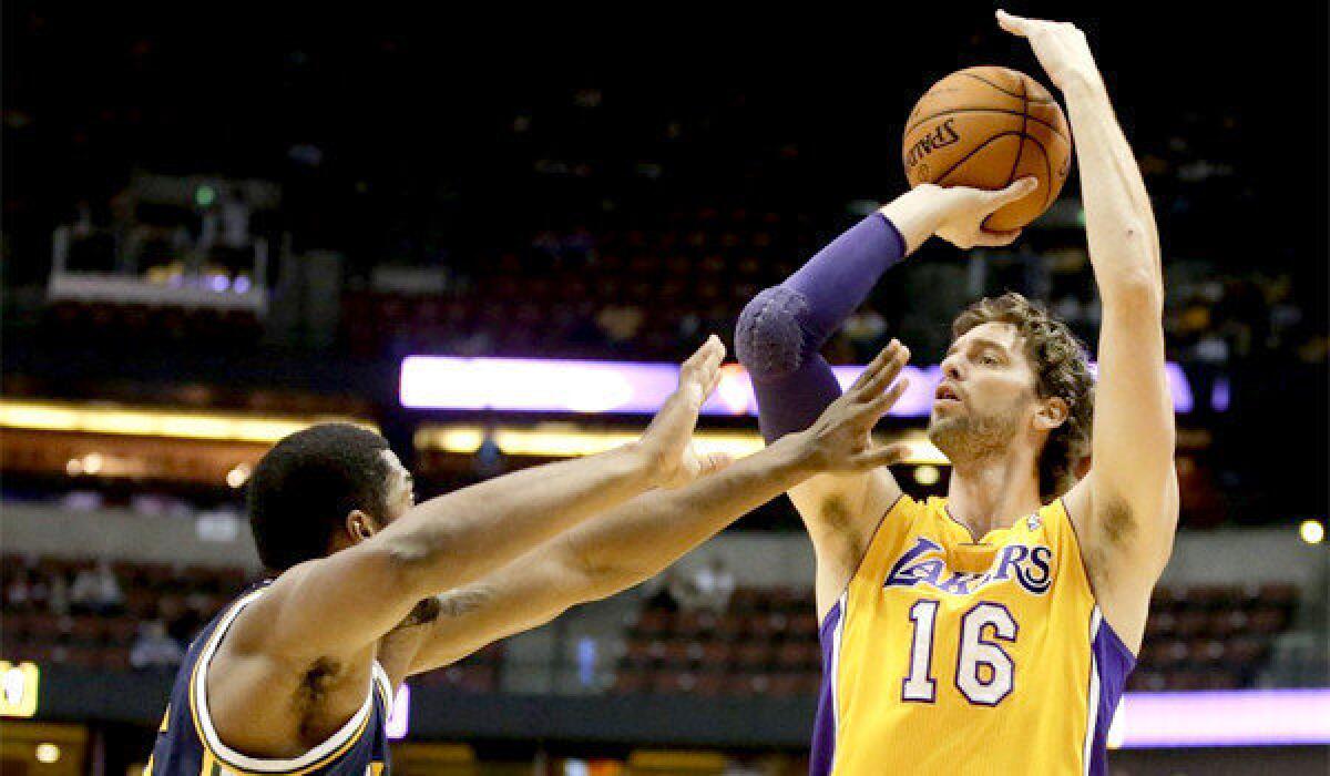 Pau Gasol shoots over Derrick Favors during the Lakers' 111-106 win over the Utah Jazz in a preseason exhibition game at the Honda Center.