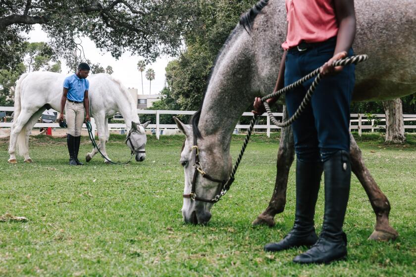 Los Angeles, CA - September 17: Julian Harrison stands with his horse "Chess," left, and his brother Cameron Harrison stands with "Buttons," right, at the Los Angeles Equestrian Center on Sunday, Sept. 17, 2023 in Los Angeles, CA. (Dania Maxwell / Los Angeles Times)