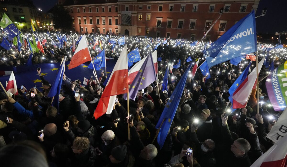 People hold up the flashlights of their mobile phones during a demonstration in support of Poland's EU membership in Warsaw, Poland, Sunday, Oct. 10, 2021. Poland's constitutional court ruled Thursday that Polish laws have supremacy over those of the European Union in areas where they clash, a decision likely to embolden the country's right-wing government and worsen its already troubled relationship with the EU. (AP Photo/Czarek Sokolowski)