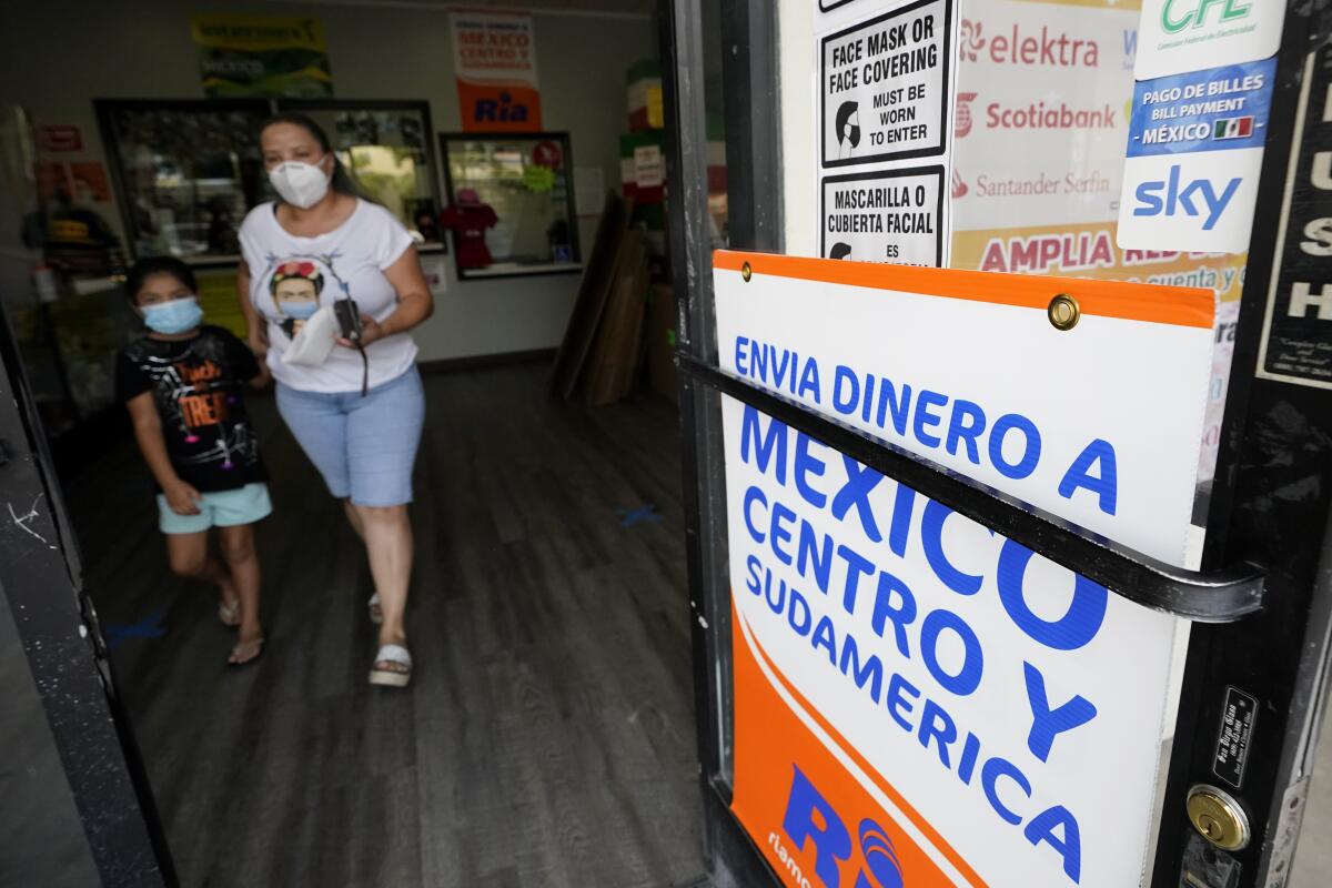 ARCHIVO - Una mujer sale de una tienda que ofrece servicios para enviar remesas a México 