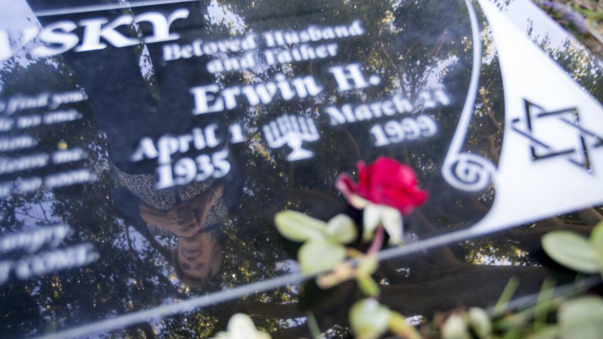 Latife Warshawsky's reflection is seen in the grave marker of her husband, Erwin, at Pacific View Memorial Park.
