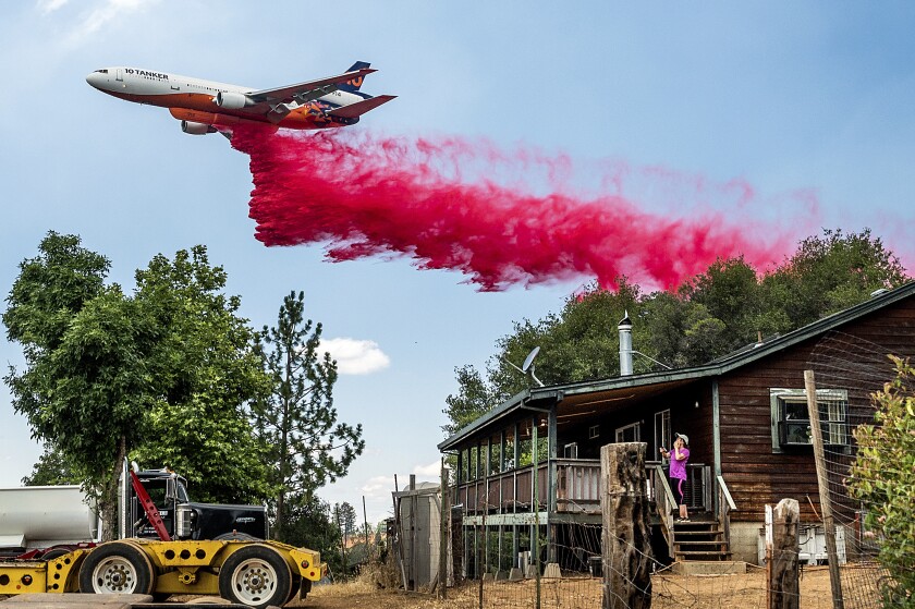 Karyn Larson observa cómo un avión cisterna lanza retardante de fuego mientras arde un incendio forestal en las cercanías de la comunidad de Pine Acres, en el condado de Amador, California, el martes 5 de julio de 2022. (AP Foto/Noah Berger)