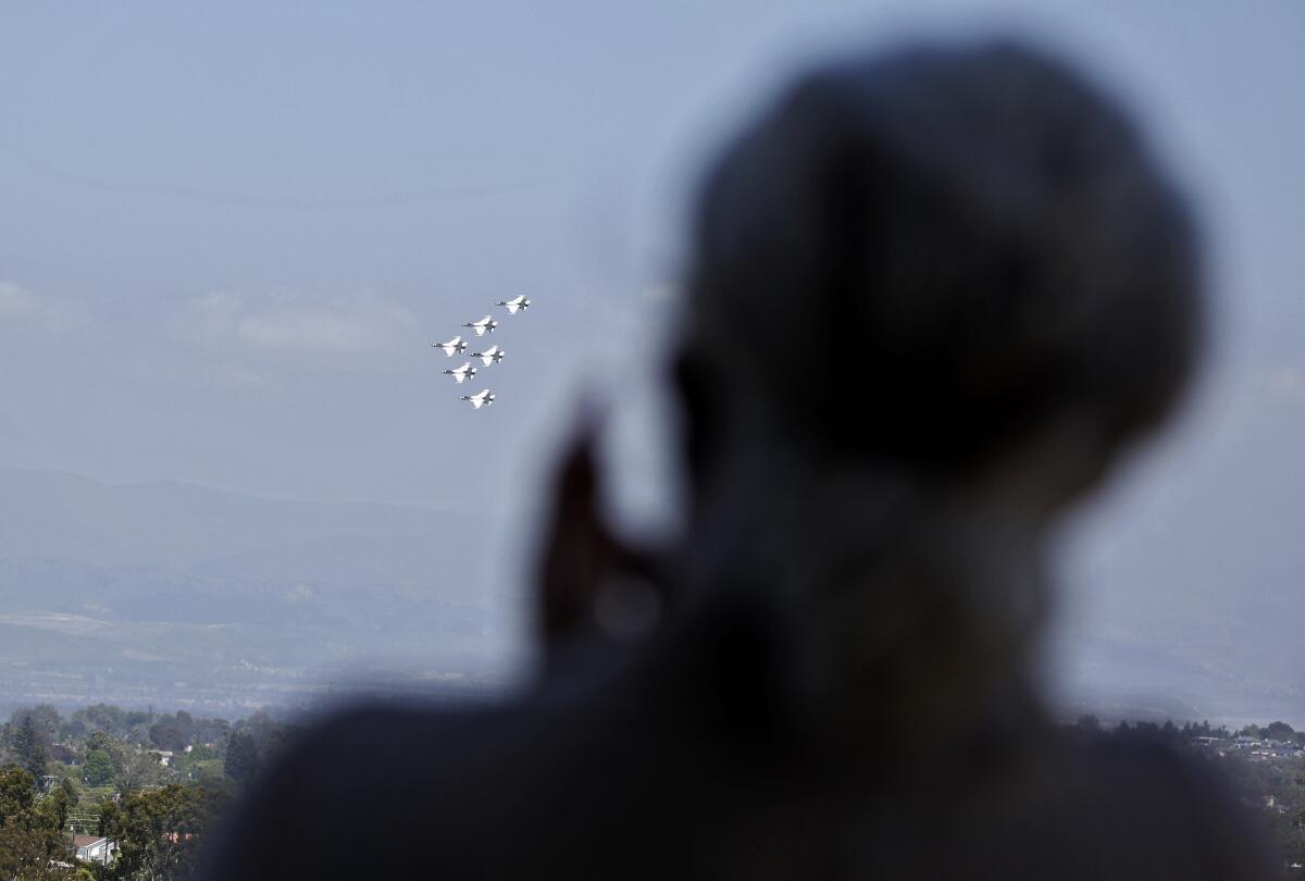 An employee of Hoag Memorial Hospital Presbyterian applauds while looking from a roof-top spot as the Thunderbirds do a fly-by to salute the state's COVID-19 first responders, in Newport Beach on Friday.