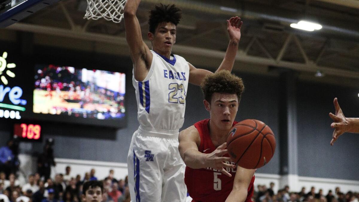 Mater Dei's Devin Askew (5) passes off after driving towards the basket in front of Santa Margarita Max Agbonkpolo (23) during the first half at Santa Margarita High School on Wednesday.