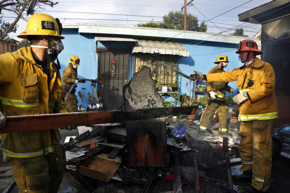 Los Angeles firefighters bring out the damaged belongings from a residence that caught fire on Tuesday morning in the 6600 block of Estrella Avenue in Los Angeles.