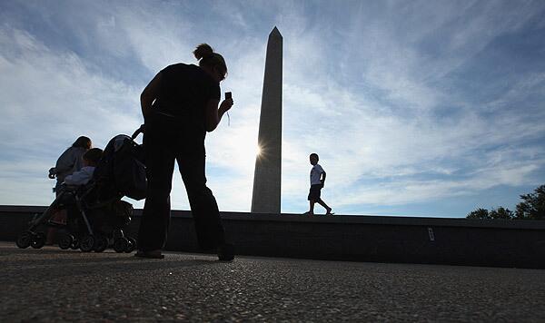 The Washington Monument, closed for damage assessment on Wednesday, is photographed by a passing woman.