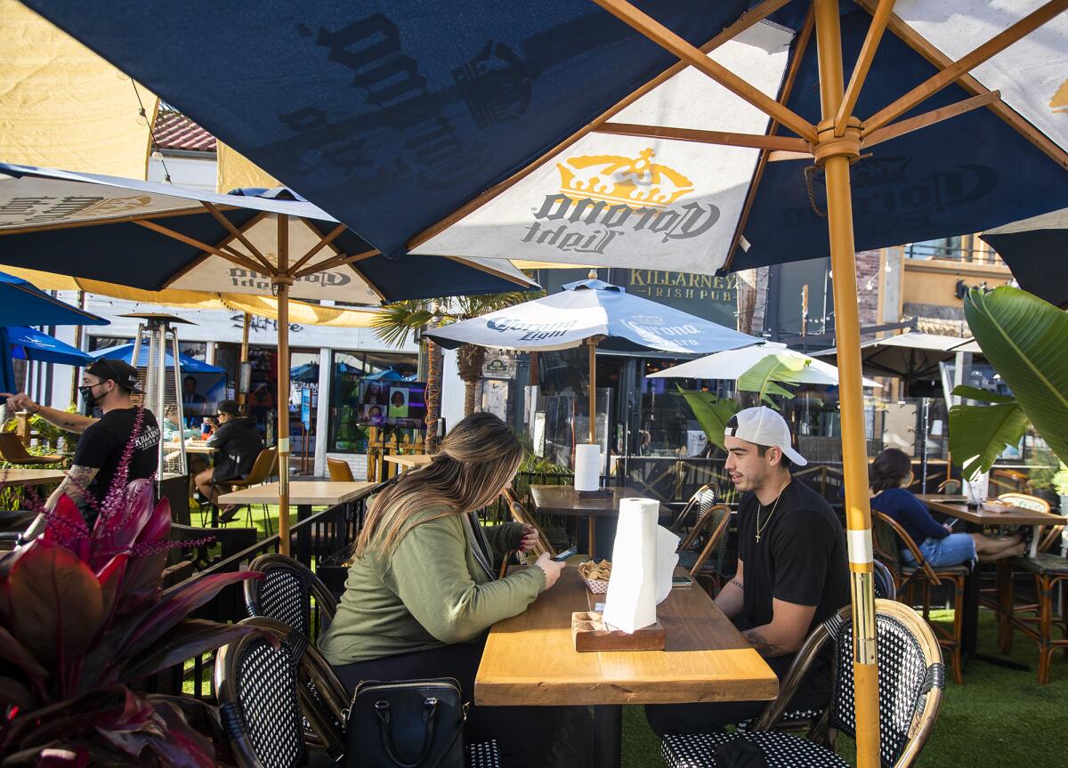 Jessica Devlahovich, left, and Anthony Derashave have lunch outside at Baja Sharkeez in Huntington Beach on Tuesday.