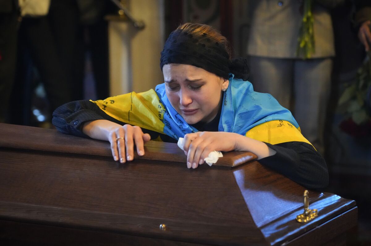 FILE - The widow cries at the coffin of volunteer soldier Oleksandr Makhov, 36 a well-known Ukrainian journalist, killed by the Russian troops, at St. Michael cathedral in Kyiv, Ukraine, Monday, May 9, 2022. According to a report released Tuesday, Jan. 24, 2023, by the New York-based Committee to Protect Journalists, killings of journalists around the world jumped by 50% in 2022 compared to the previous year, driven largely by murders of reporters in the three deadliest countries: Ukraine, Mexico and Haiti. (AP Photo/Efrem Lukatsky, File)