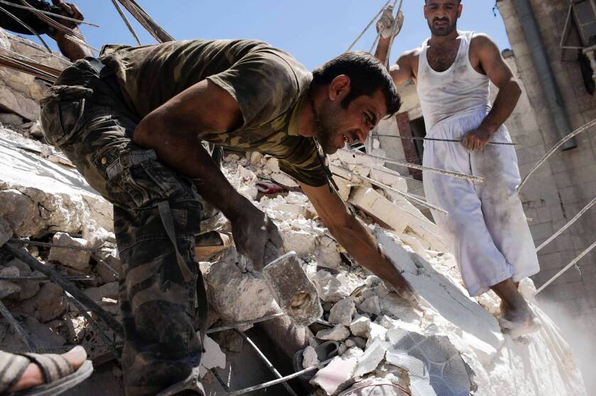 Syrians in Aleppo try to remove the body of a man buried under the rubble of a building bombed by a warplane.